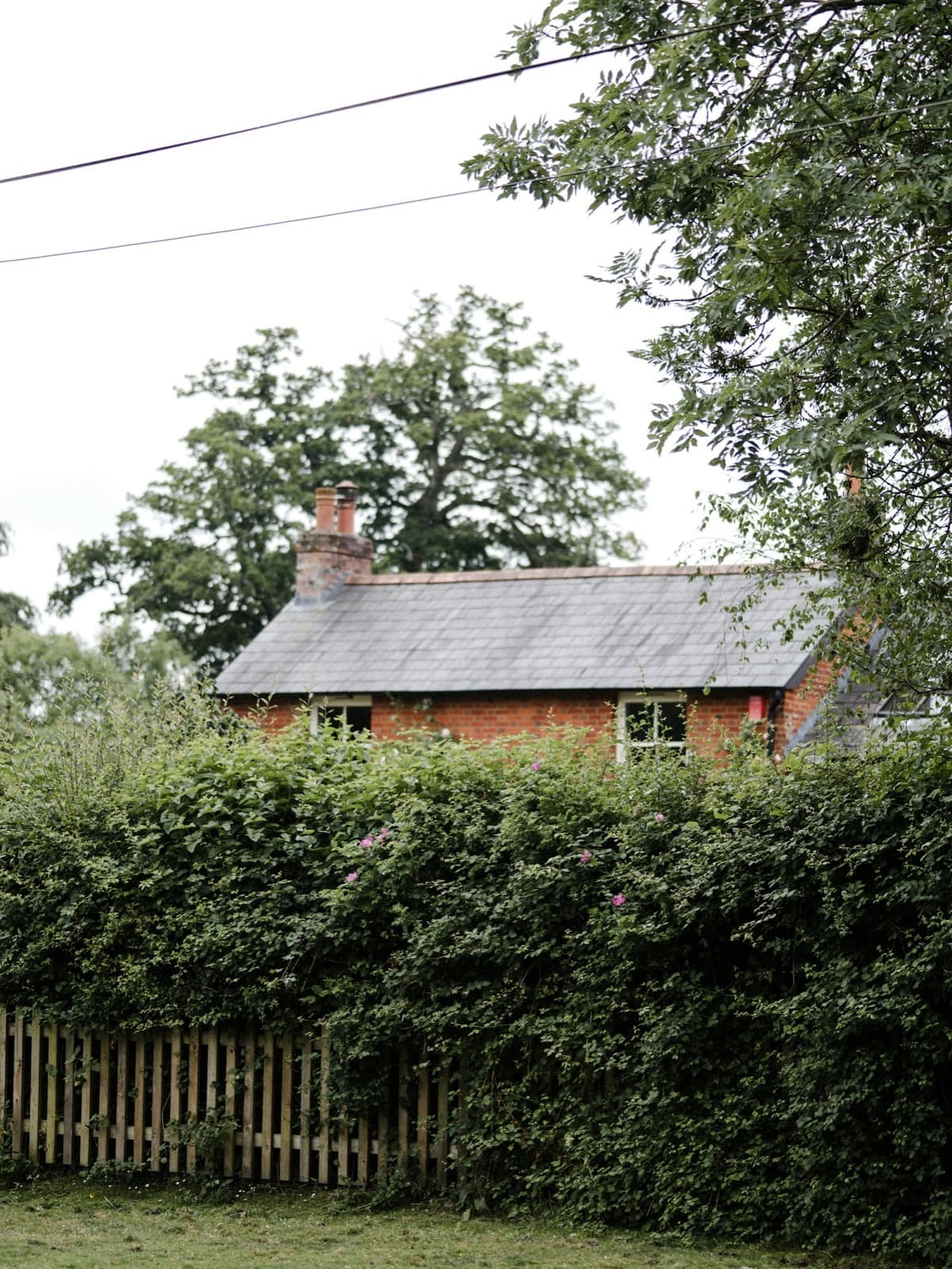A timber fence beside a red-brick country cottage